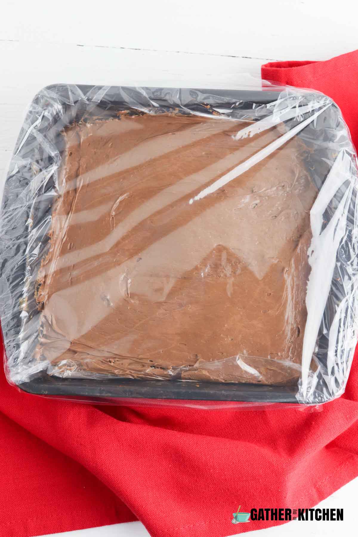 Melted chocolate in a baking pan covered in plastic wrap.
