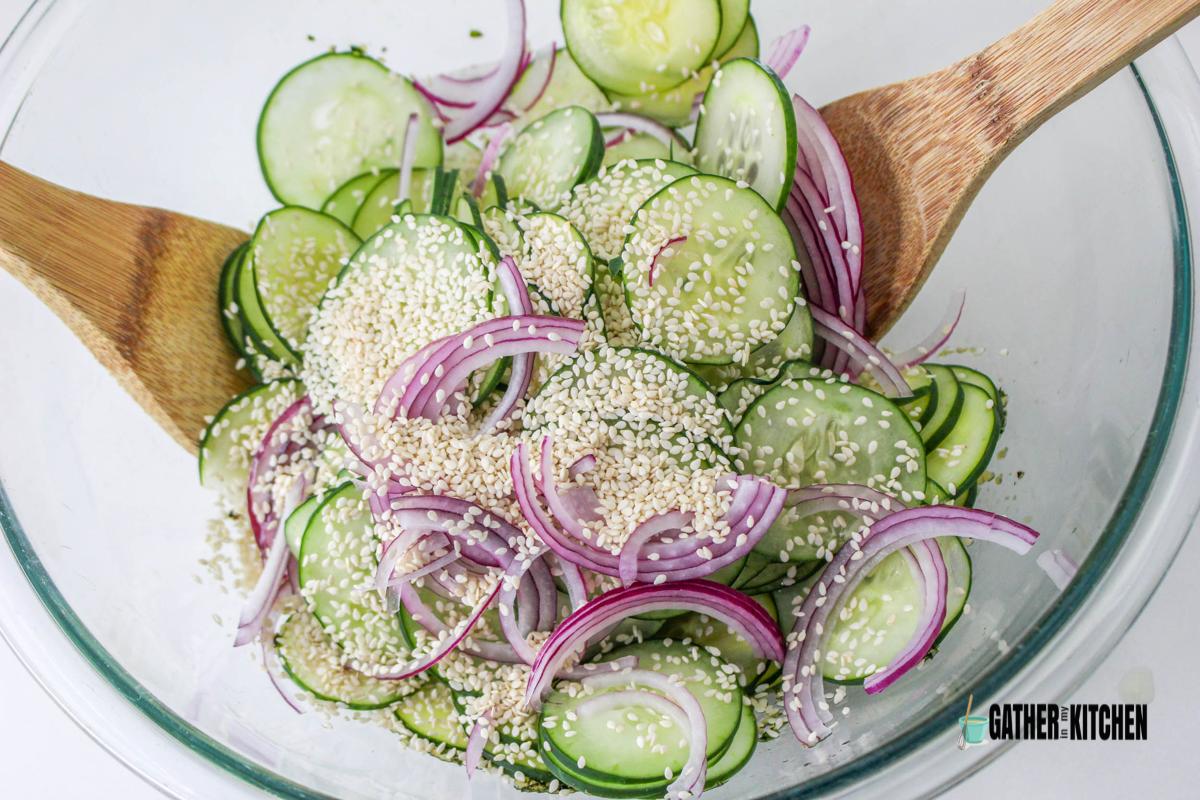 Sesame seeds on top of onions and cucumbers in a bowl.