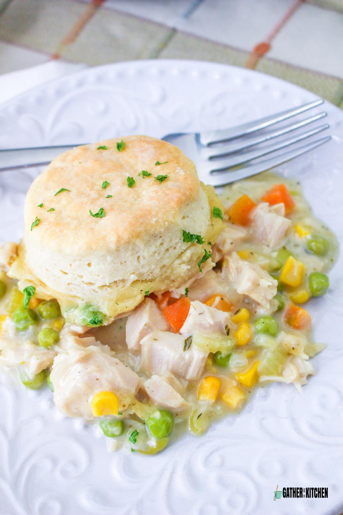 A plate of Turkey Pot Pie with biscuit on plate with a fork.
