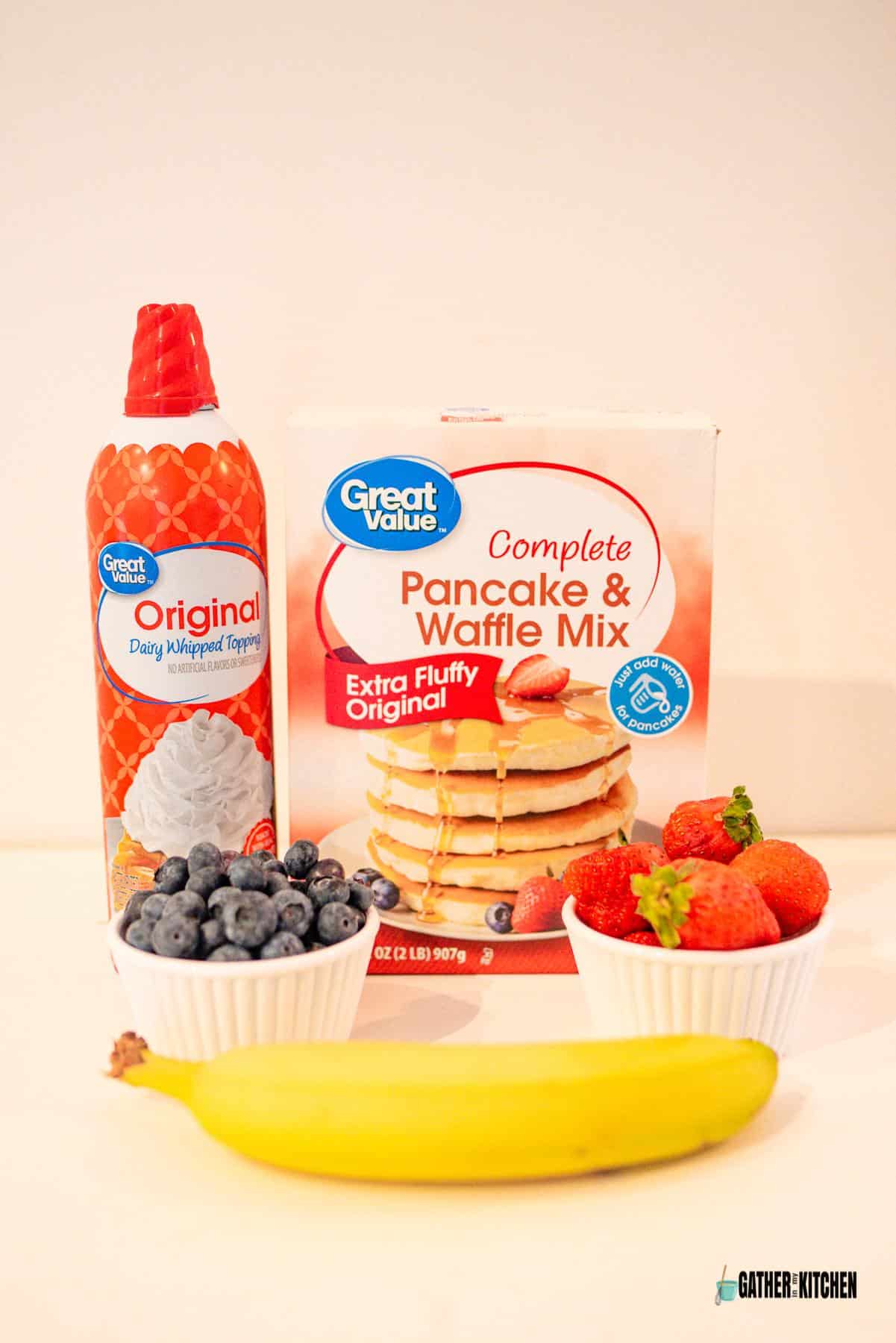 Ingredients for bunny face pancakes: whipped topping, pancake mix, blueberries, strawberries and banana.