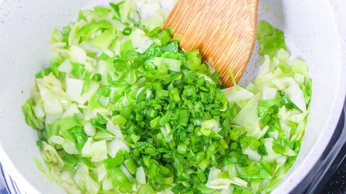 Green onions added to cabbage mixture in pan.