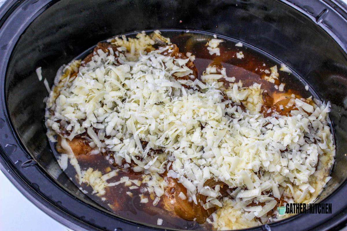 Cooked chicken with shredded cheese added to slow cooker.