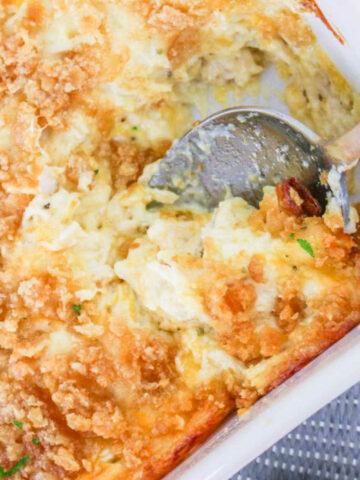 Million dollar chicken casserole in a casserole dish with a serving spoon.