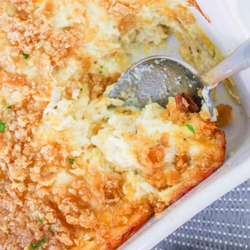 Million dollar chicken casserole in a casserole dish with a serving spoon.