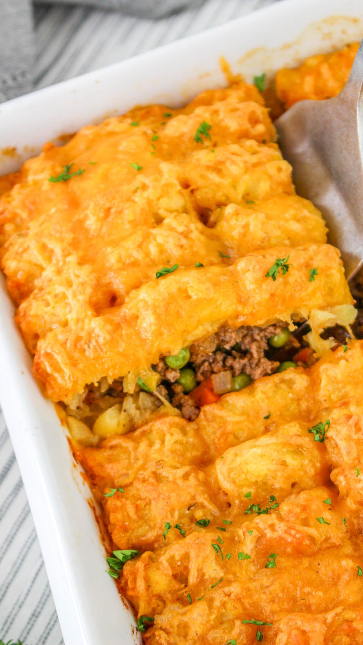 Slide of shepherds pie with tater tots being lifted out of the casserole dish.