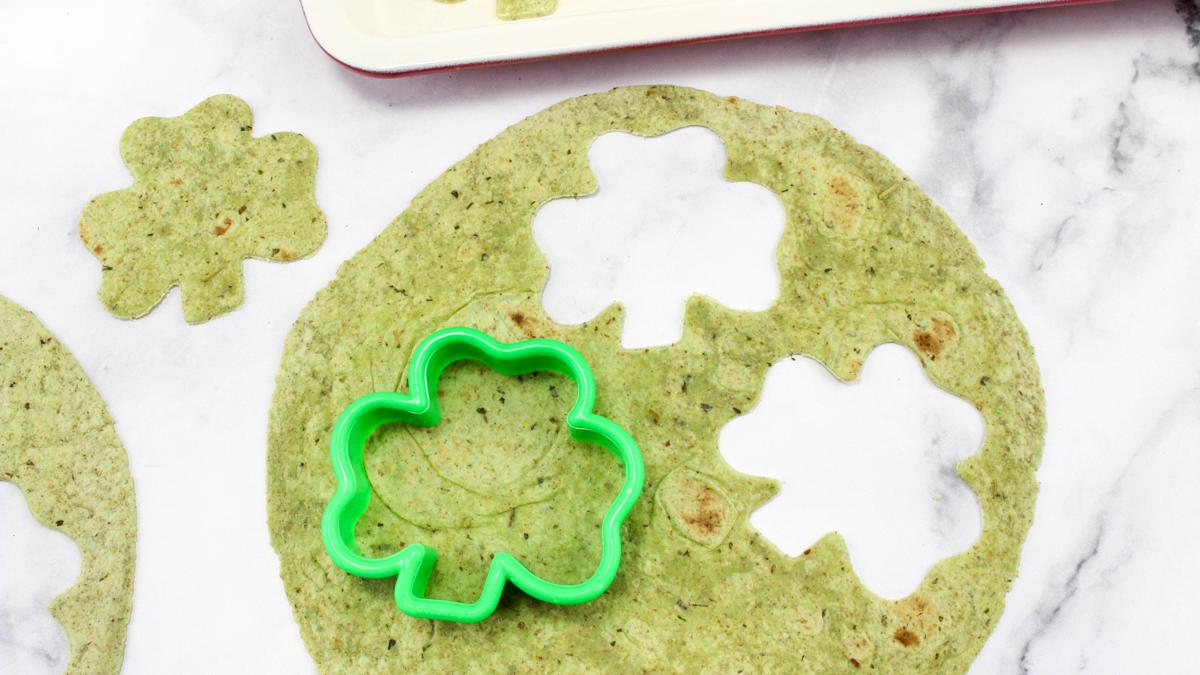4-leaf clover cookie cutter on a tortilla with a couple shaped tortillas cut out.