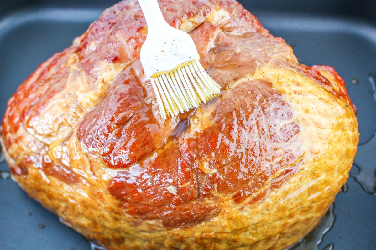 Basting ham with brown sugar glaze.