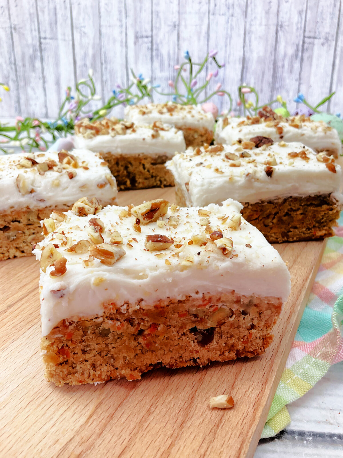 Side view of carrot cake bars on a cutting board.