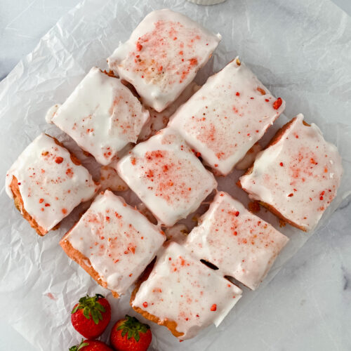 Top down view of strawberry blondies cut on parchment paper.