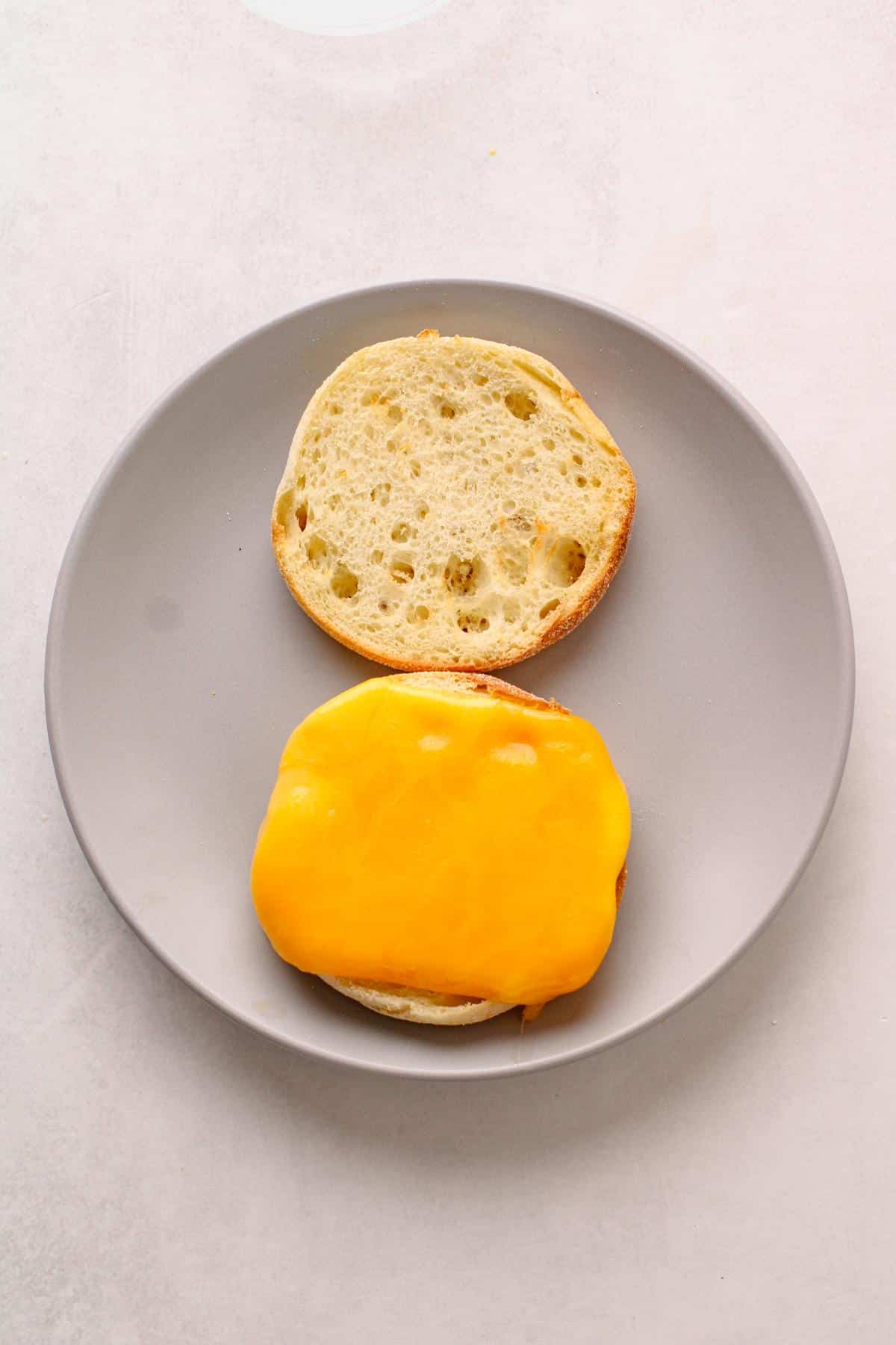 English muffin on plate with cheese on top.