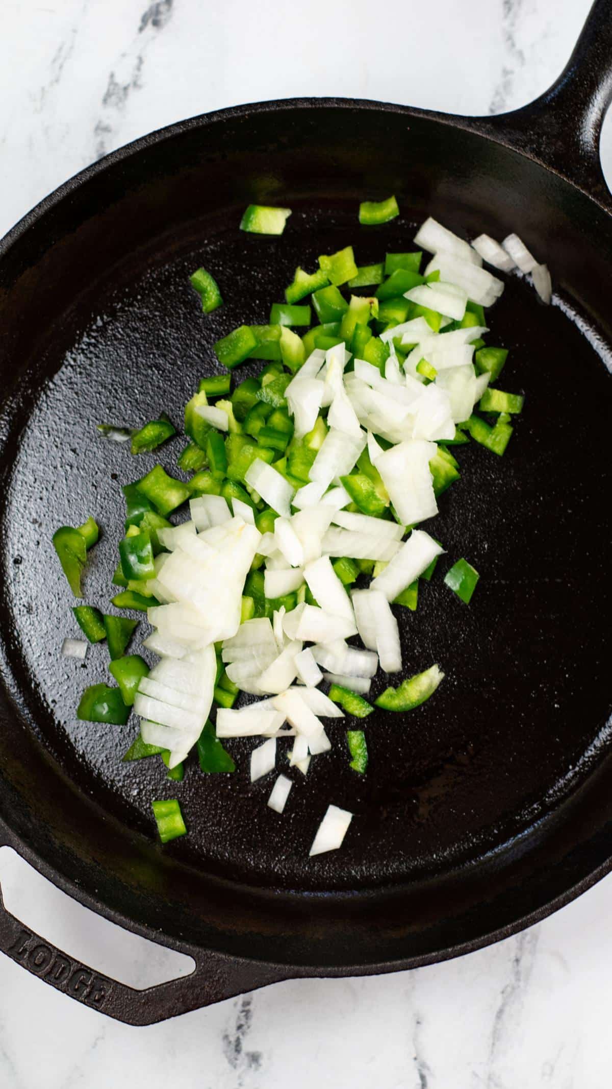 Cast iron pan with green bell pepper and onion.