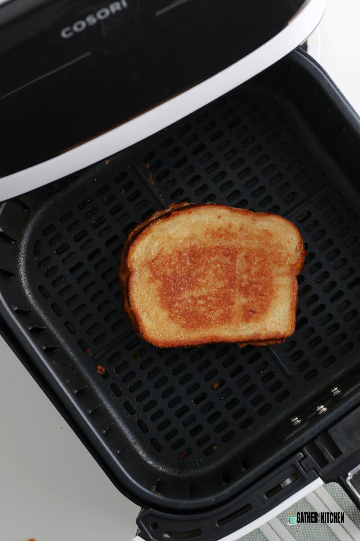 Cooked grilled cheese sandwich in air fryer basket.