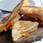5 halves of air fryer grilled cheese sandwiches on a cutting board.