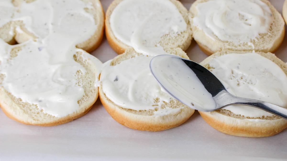 Ranch spread on bottom of slider buns with spoon next to them.