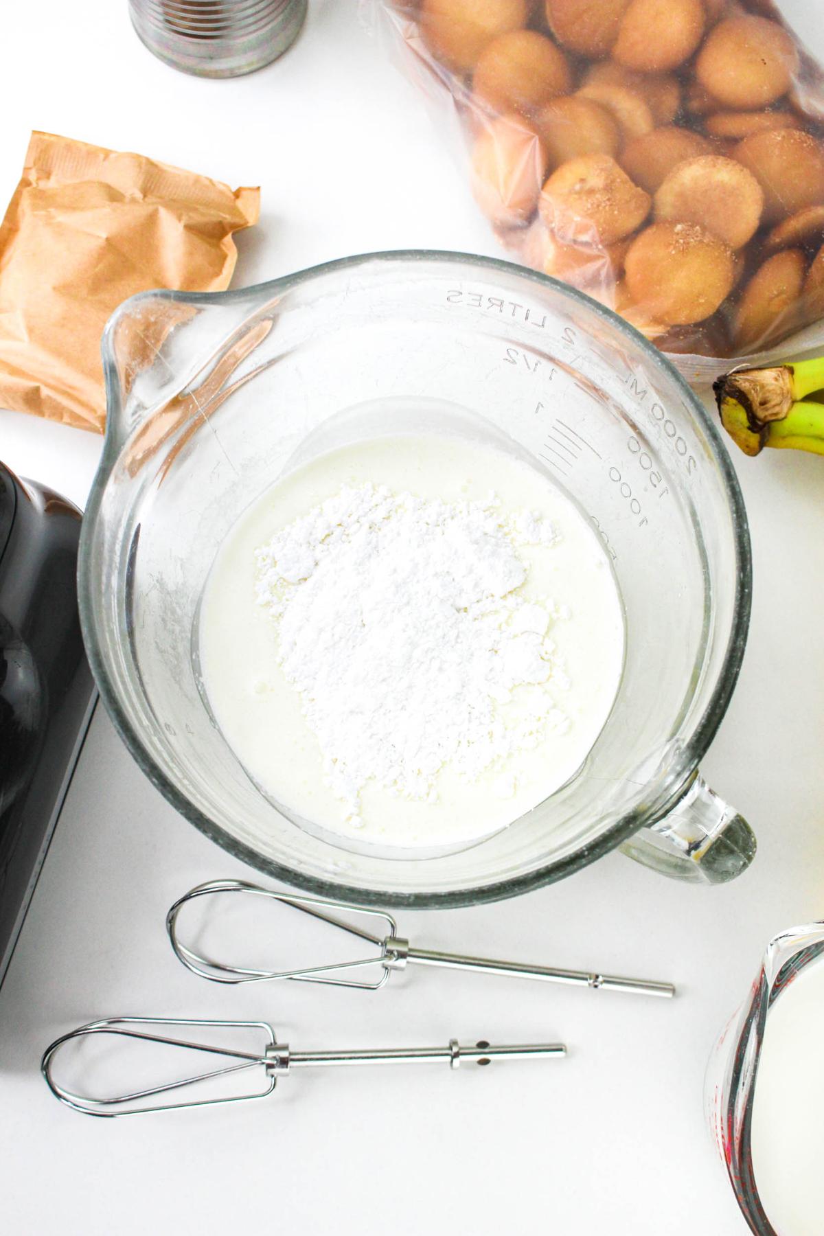 Heavy whipping cream and powdered sugar in a measuring cup.