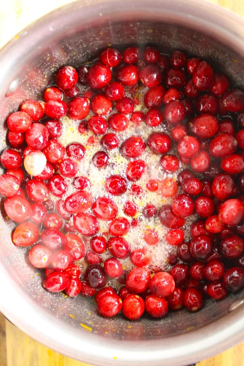 Top down view of a saucepan with the cranberry sauce ingredients at a rolling boil.